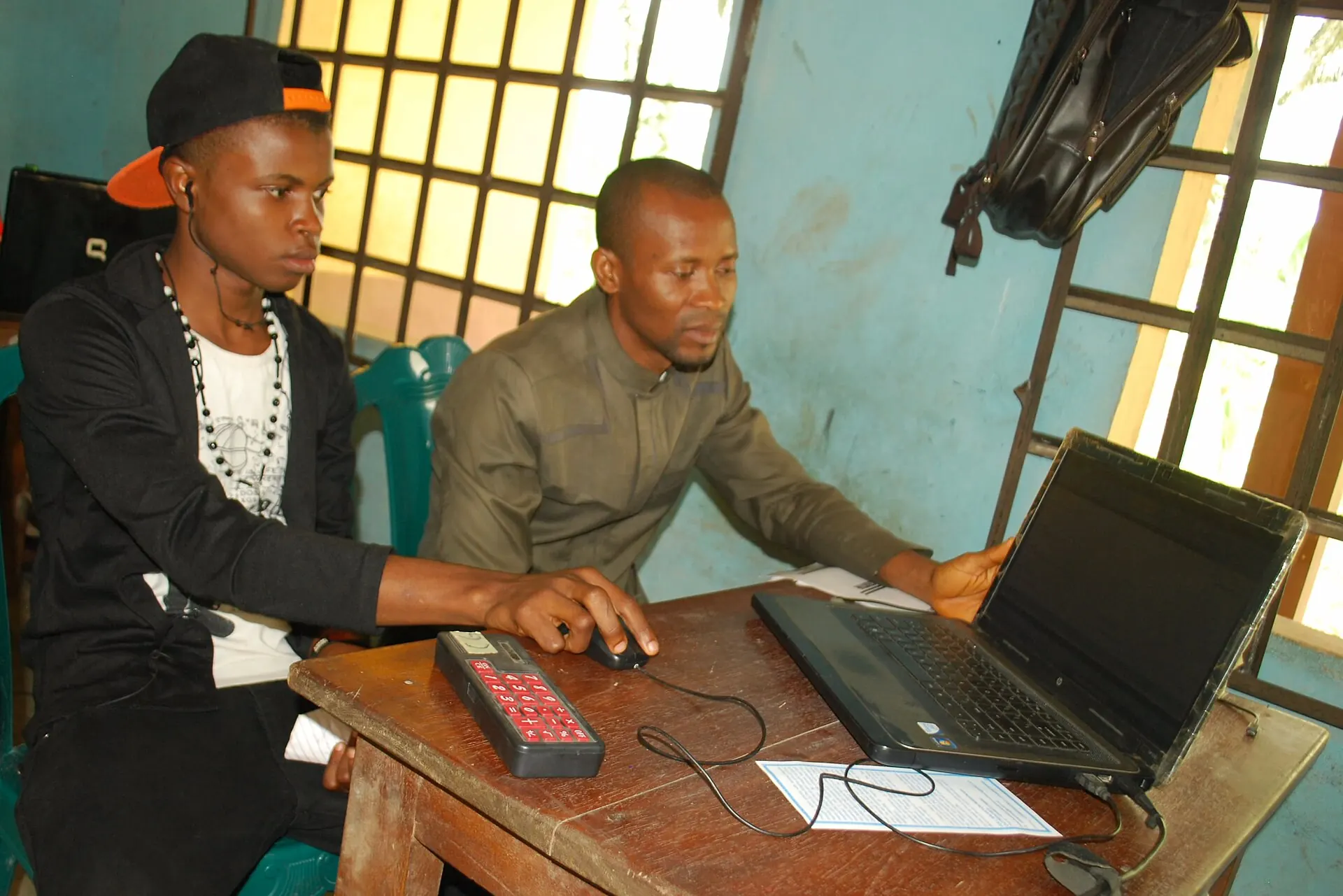 Two men studying at a laptop in a computer-based testing centre in Nigeria